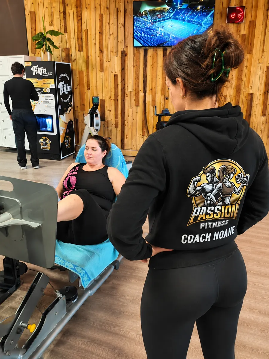 Noane, coach de Passion Fitness, accompagne une adhérente sur une machine du plateau